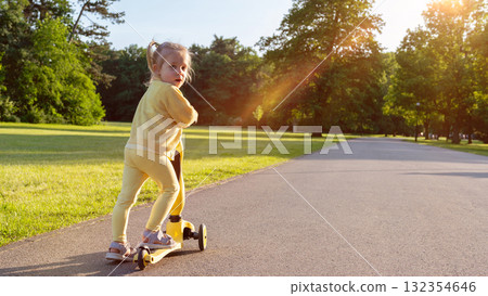 Child riding. Scooter toddler park play. Summer road motion casual sport. 132354646