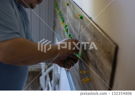 Professional worker carefully installing new ceramic tiles on a bathroom wall using tile leveling clips, ensuring a precise and even finish during interior home improvement work. 132354806
