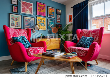 A pair of red upholstered chairs with a tropical print cushion and throw pillow in front of colorful framed posters on blue walls 132355261