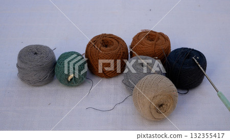 Many skeins with cotton crochet threads on the table in brown-gray tones.  Many skeins with cotton crochet threads on the table in brown-gray tones.  132355417