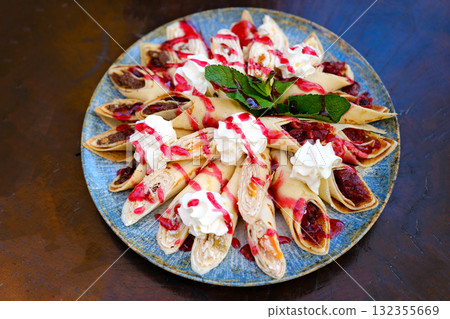 Crepes stuffed with chocolate spread and banana on white plate. Thin pancakes, blini. Sweet dessert. Crepes stuffed with chocolate spread and banana on white plate. Thin pancakes, blini. Sweet dessert. 132355669