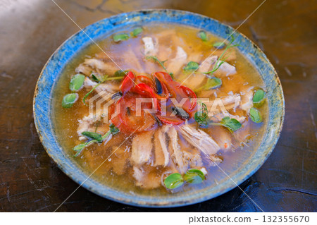 Chicken aspic, a traditional cold savory appetizer, served in portion form on a plate placed on a wooden table. Polish cuisine and Eastern European culinary tradition. Top view. Close-up. 132355670