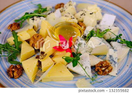 Plate with different types of cheese, nuts, honey and grapes on grunge background 132355682