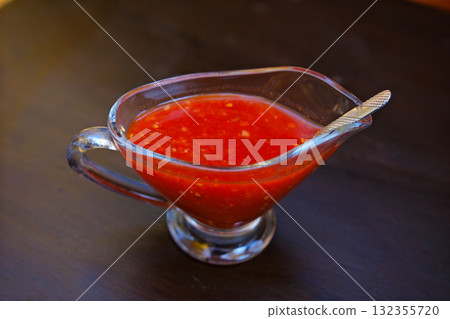 Spoon with tomato sauce and tomatoes on a table 132355720
