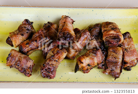 Bacon wrapped chicken drumsticks in a black cast-iron skillet on the stone background. Bacon wrapped chicken drumsticks in a black cast-iron skillet on the stone background. 132355813