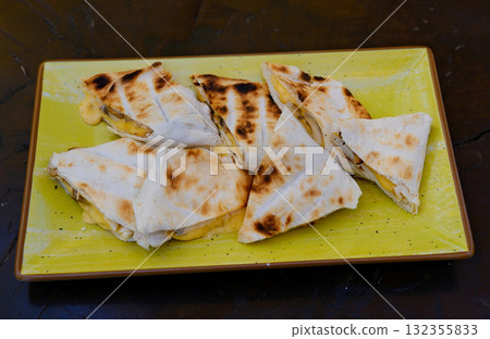 Grilled quesadillas on wooden board and with salsa and guacamole on stone background. Mexican cuisine concept Quesadilla wrap with chicken and corn. Top view 132355833