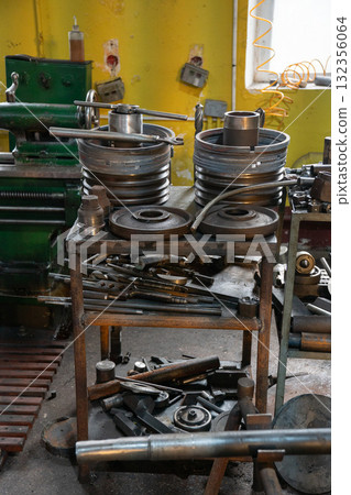 Metal flanges, couplings, and machining tools arranged on a workbench inside the locomotive museum Povorotny Krug Metal flanges, couplings, and machining tools arranged on a workbench inside the locomotive museum Povorotny Krug 132356064
