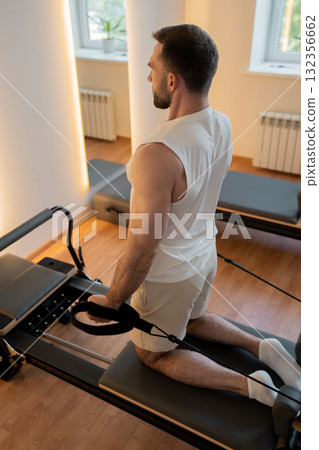 Close up hand man Core body muscles, man doing Pilates exercises to strengthen body and stretch. practicing physical fitness exercises on Pilates machine. Reformer pilates studio machine for workouts 132356662
