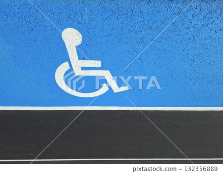 Brightly painted disabled person sign on new asphalt marking shows a clear symbol indicating accessibility in a parking space. This fresh marking enhances visibility for drivers. 132356889