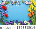 Beautiful floral frame on a vibrant blue background, featuring a colorful assortment of spring flowers 132356914