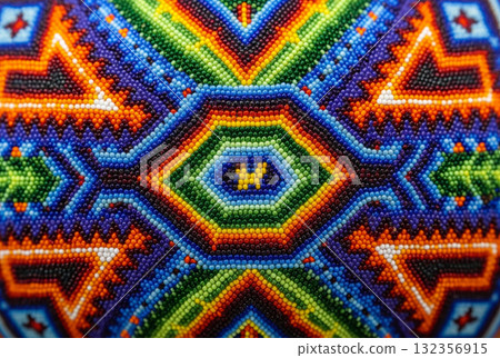 An extreme close-up, macro shot of a brightly coloured piece of intricate beadwork or mosaic, consistent with traditional Huichol art from Mexico. An extreme close-up, macro shot of a brightly coloured piece of intricate beadwork or mosaic, consistent with traditional Huichol art from Mexico. 132356915