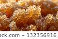 An extreme macro close-up photograph showcasing the complex crystallized texture of honey, illuminated by warm, intense golden hour light.  132356916