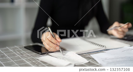 Business professional organizing finances with a notebook and smartphone Business professional organizing finances with a notebook and smartphone 132357108