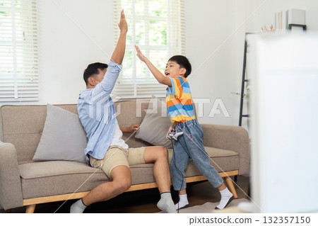 Family Bonding and Playtime. A father and son engaging in a fun high-five moment at home. 132357150