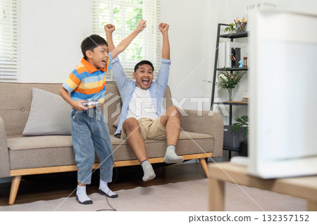 Family Fun and Gaming. A father and son celebrate a gaming victory together on the couch. 132357152
