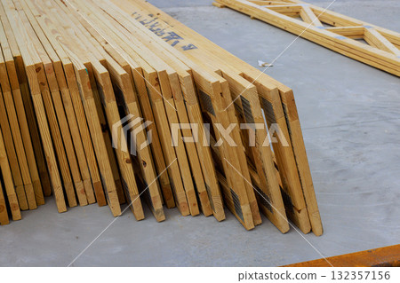 Piles of wooden roofing joins beams lined up at construction site for building work. 132357156
