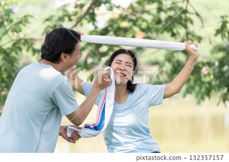 Wellness and Senior Joy. A senior couple playfully engaging in a light-hearted moment while exercising outdoors. 132357157