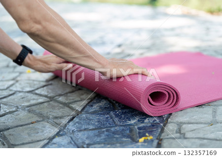 Wellness in Yoga: Senior preparing yoga mat outdoors 132357169