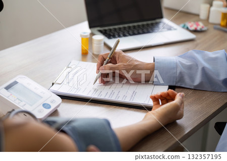 Patient consultation with doctor filling out medical paperwork Patient consultation with doctor filling out medical paperwork 132357195