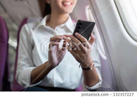 Business travel: Woman checking smartphone on the airplane 132357227