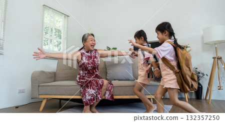 Excitement and Family Reunion. Grandmother joyfully welcomes her granddaughters as they rush to her with open arms. 132357250