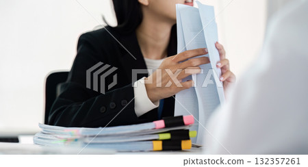 Documentation and Attention to Detail. A woman highlights important aspects of a report during a business discussion. 132357261