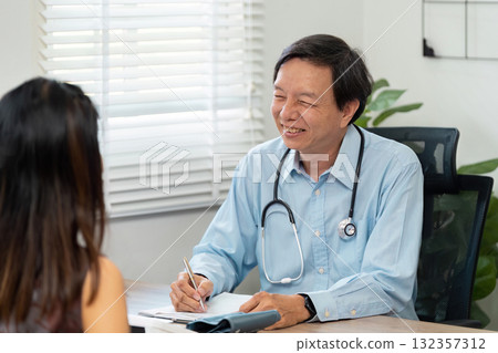 Healthcare and Patient Consultation. A smiling doctor engaging with a patient during a medical consultation in a professional setting. Healthcare and Patient Consultation. A smiling doctor engaging with a patient during a medical consultation in a professional setting. 132357312