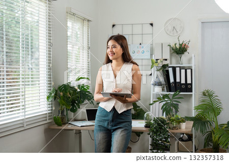 Business woman smiling while holding a tablet in a modern office 132357318