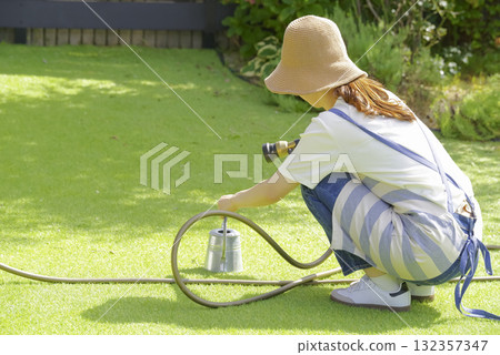 A woman watering a planter with a watering can 132357347