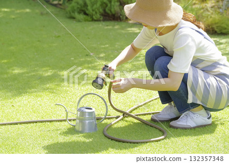 A woman watering a planter with a watering can 132357348