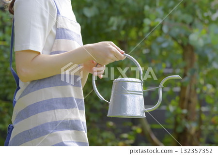 一名婦女用噴壺給花盆澆水 一名婦女用噴壺給花盆澆水 132357352