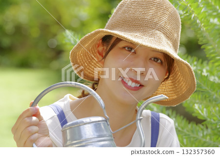 A woman watering a planter with a watering can 132357360
