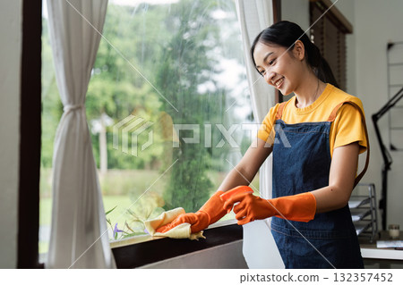 Cleaning woman happily wiping window with cloth and gloves Cleaning woman happily wiping window with cloth and gloves 132357452