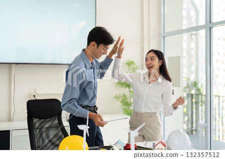 Collaboration and Achievement in Engineering. Engineers celebrating a successful project discussion focused on sustainability and innovation. 132357512