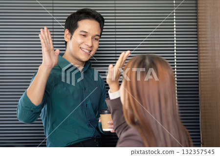 Business Interaction and Professional Networking. A friendly greeting between colleagues in an office setting. 132357545