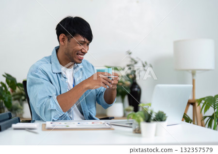 Remote Work and Sustainability. A young professional enjoying a coffee break while working from home in a green environment. 132357579
