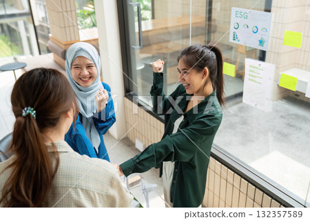 Team Collaboration and ESG Success. Three women celebrating their achievements in a sustainable business environment. Team Collaboration and ESG Success. Three women celebrating their achievements in a sustainable business environment. 132357589