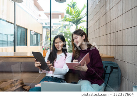 Friendship and Learning. Two students collaborating on a group project at a trendy cafe. Friendship and Learning. Two students collaborating on a group project at a trendy cafe. 132357604