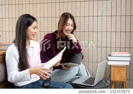 Study Session and Friendship. Friends collaborating on schoolwork, utilizing modern technology in a cozy study spot. 132357673