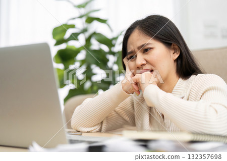 Challenges and Work Stress. A woman contemplates over her laptop, reflecting the challenges of remote work. 132357698