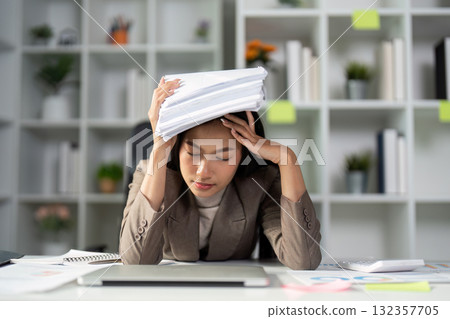 Office Stress and Overwhelm. A woman feeling overwhelmed by paperwork, managing stress in a busy office environment. 132357705