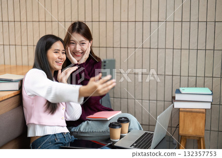 Back to College and Friendship. Two students enjoying their time while taking a selfie together in a cozy study area. Back to College and Friendship. Two students enjoying their time while taking a selfie together in a cozy study area. 132357753