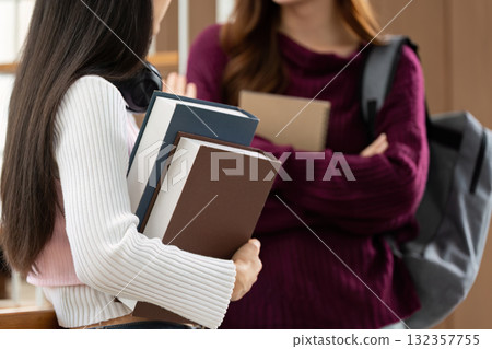 Back to College and Student Life. Two college students engaging in a discussion, holding study materials in a modern campus environment. Back to College and Student Life. Two college students engaging in a discussion, holding study materials in a modern campus environment. 132357755