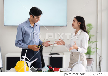 Engineering and Sustainable Solutions. Engineers engaging in a discussion about eco-friendly architecture models. 132357769