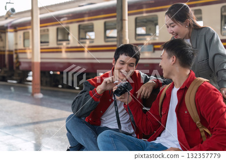 Creativity and Connection. Friends gather around a camera, sharing memories and experiences at the train station. Creativity and Connection. Friends gather around a camera, sharing memories and experiences at the train station. 132357779