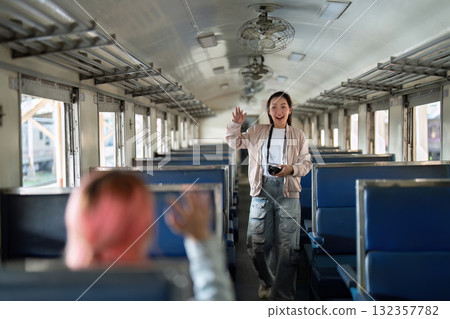 Exploration and Experience. A young woman waves excitedly in an empty train car, ready for her next adventure. Exploration and Experience. A young woman waves excitedly in an empty train car, ready for her next adventure. 132357782