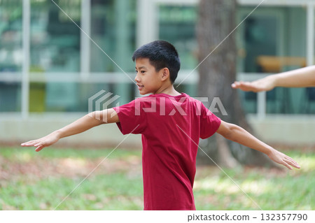 Active Play and Movement. A boy practices balance and stretches during fun outdoor exercises with his mom. Active Play and Movement. A boy practices balance and stretches during fun outdoor exercises with his mom. 132357790