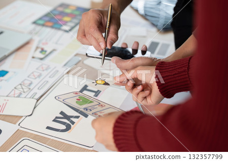 Collaboration and UX Design. Team members discussing and brainstorming UX ideas using design prototypes. 132357799