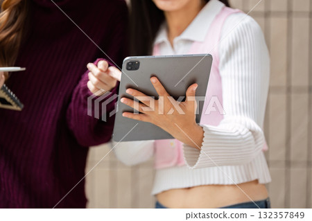 Study Practices and Technology. Students engaged in coursework discussion, utilizing a tablet for research. Study Practices and Technology. Students engaged in coursework discussion, utilizing a tablet for research. 132357849