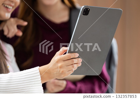 Engagement and Focus. Two college students keenly view content on a tablet, highlighting their commitment to learning. 132357853